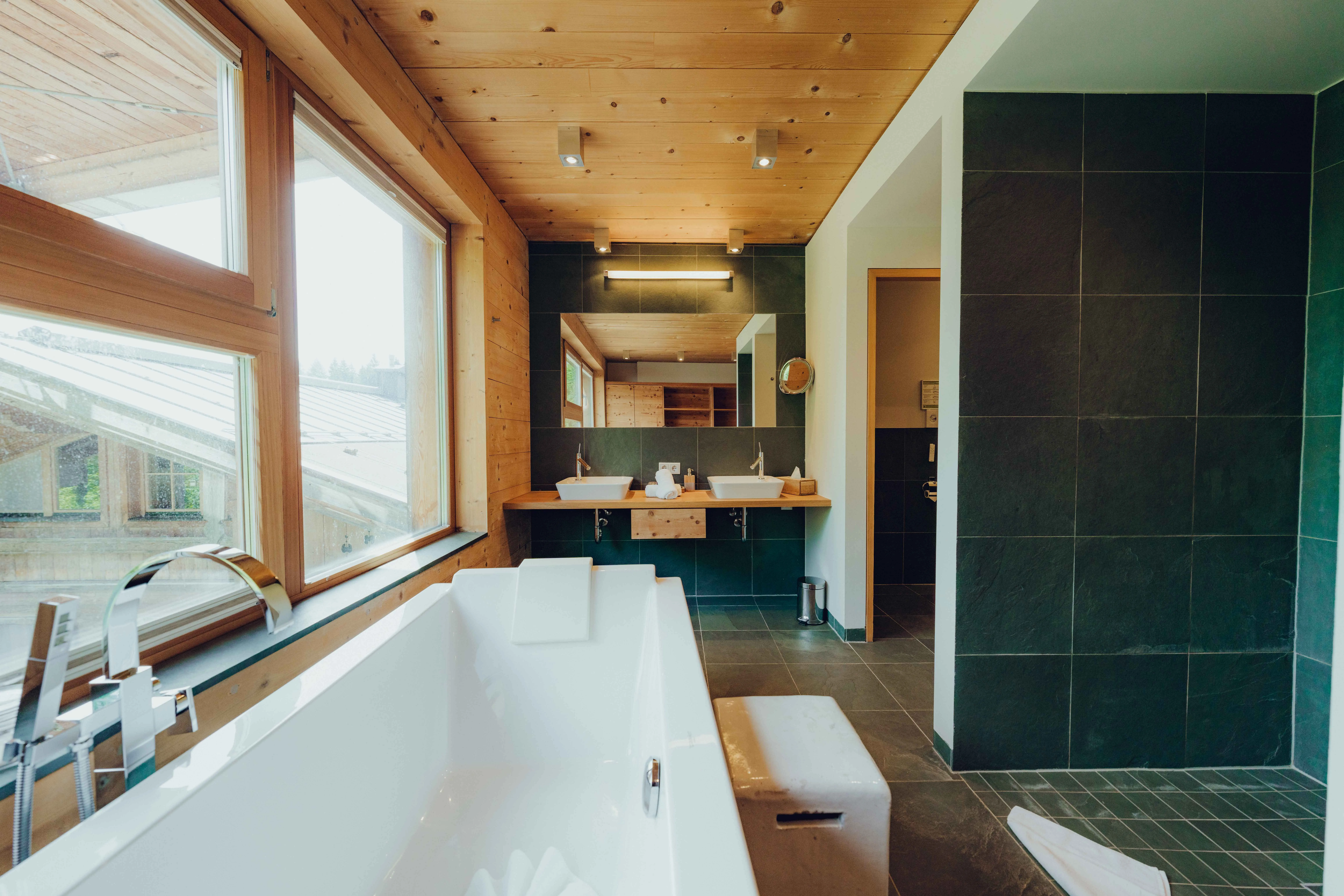 Bright bathroom with bathtub, wooden ceiling, and modern fixtures