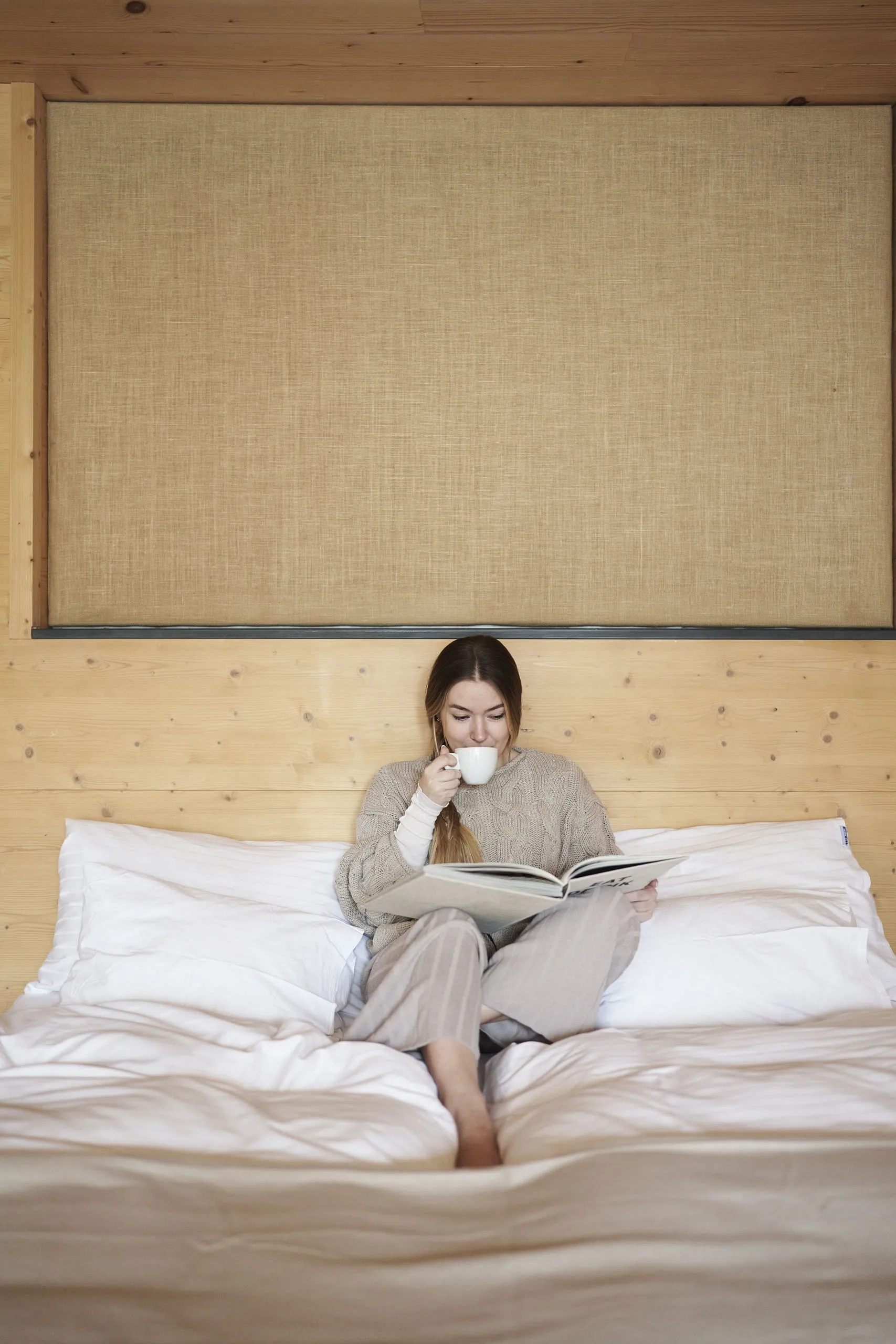 Woman sitting on bed in Holzhotel Forsthofalm reading a book