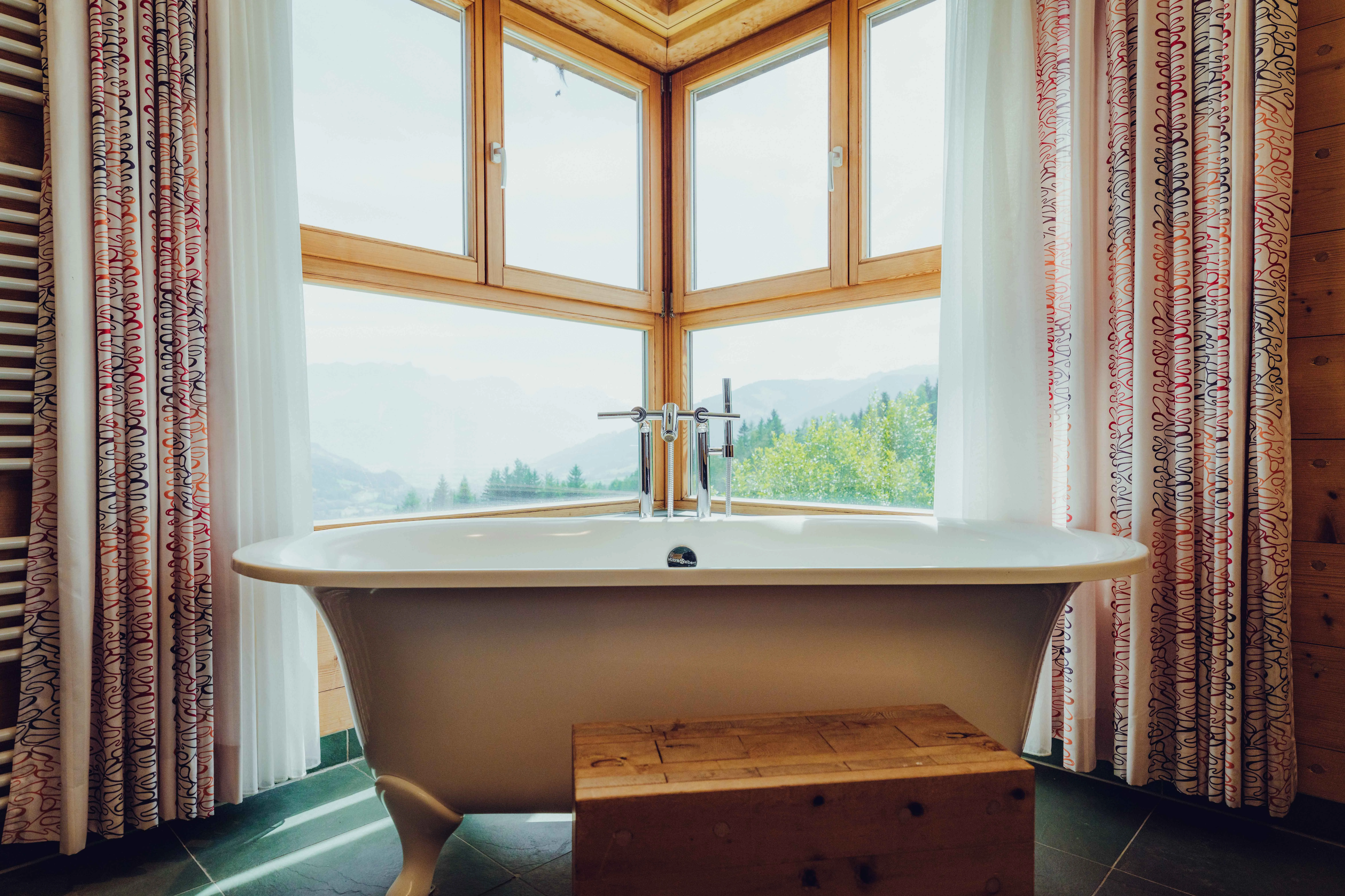 Bathtub in a bright room with large windows and a mountain view.