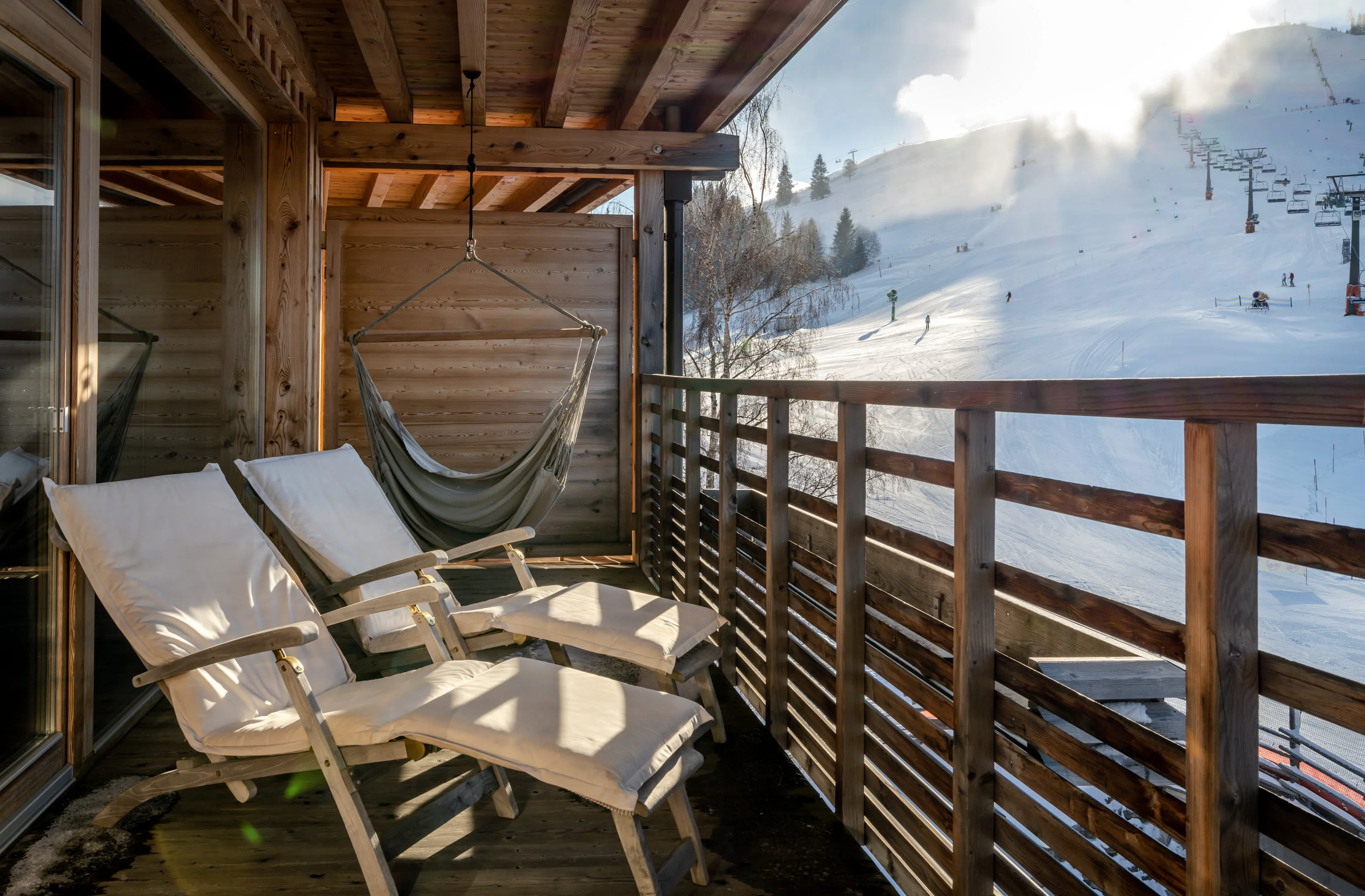 Wooden hotel balcony with two loungers overlooking a snowy landscape