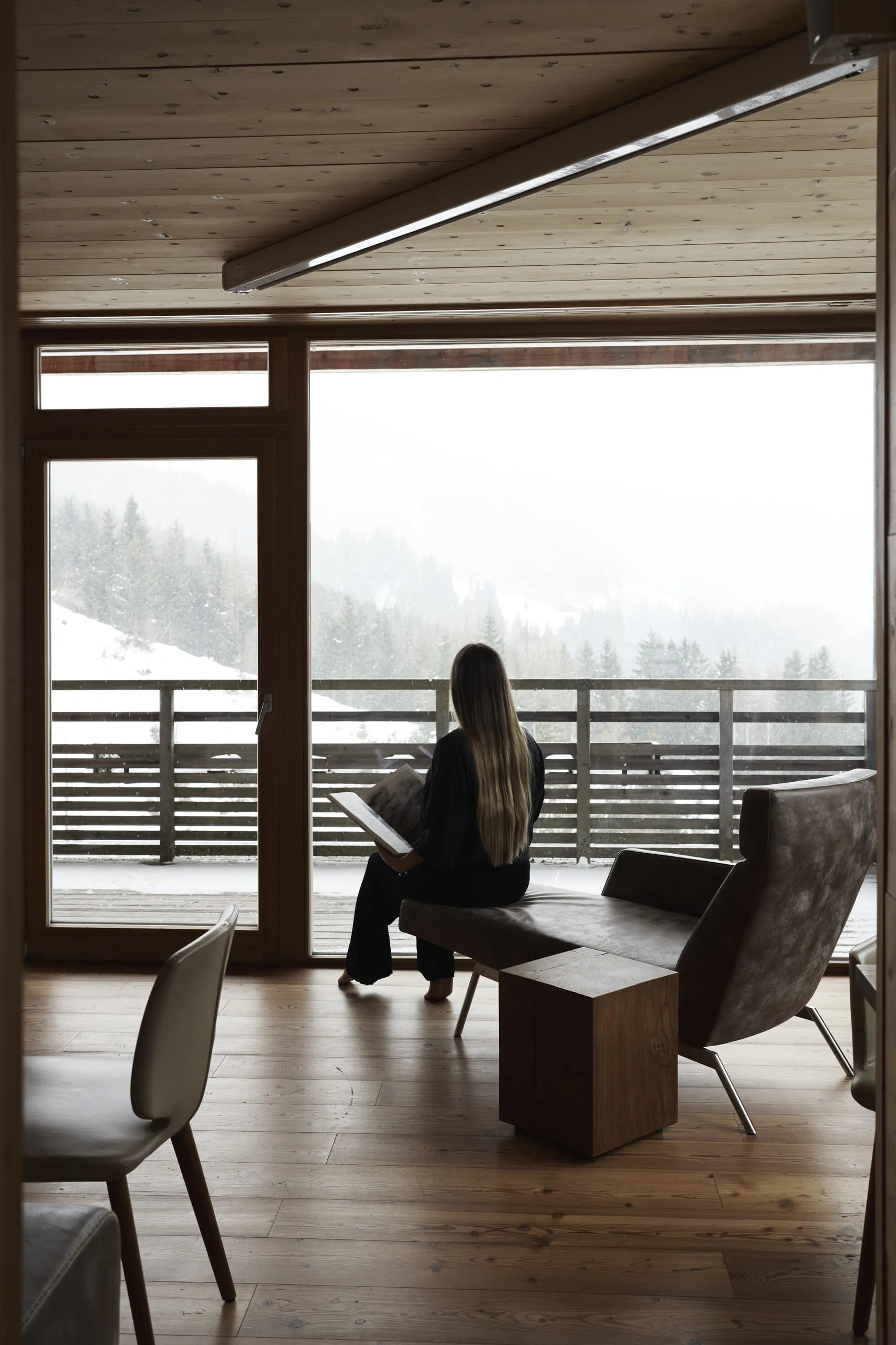 Modern interior of a wooden hotel with a view of the snowy landscape.