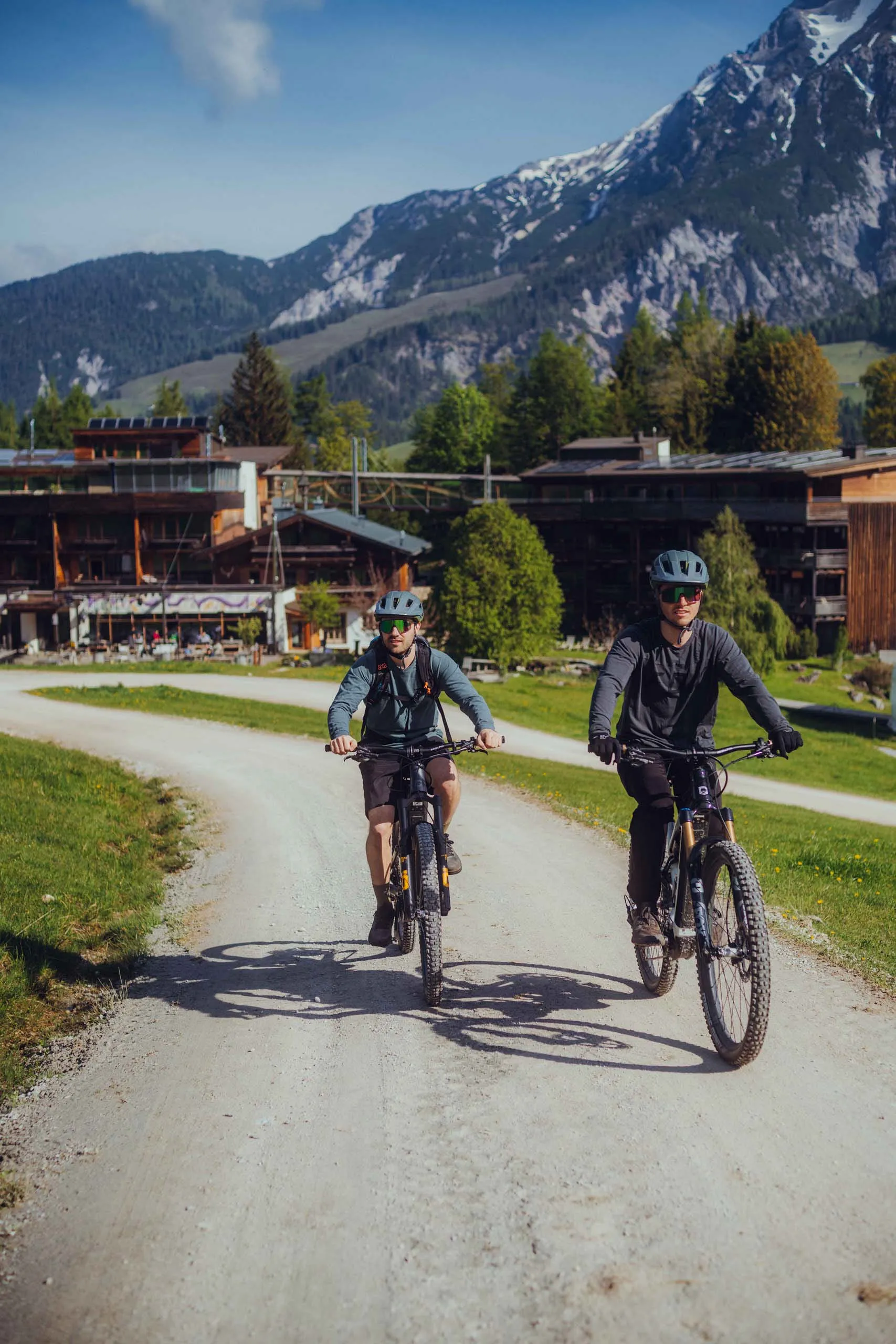 Zwei Radfahrer auf einem Schotterweg mit Bergen im Hintergrund