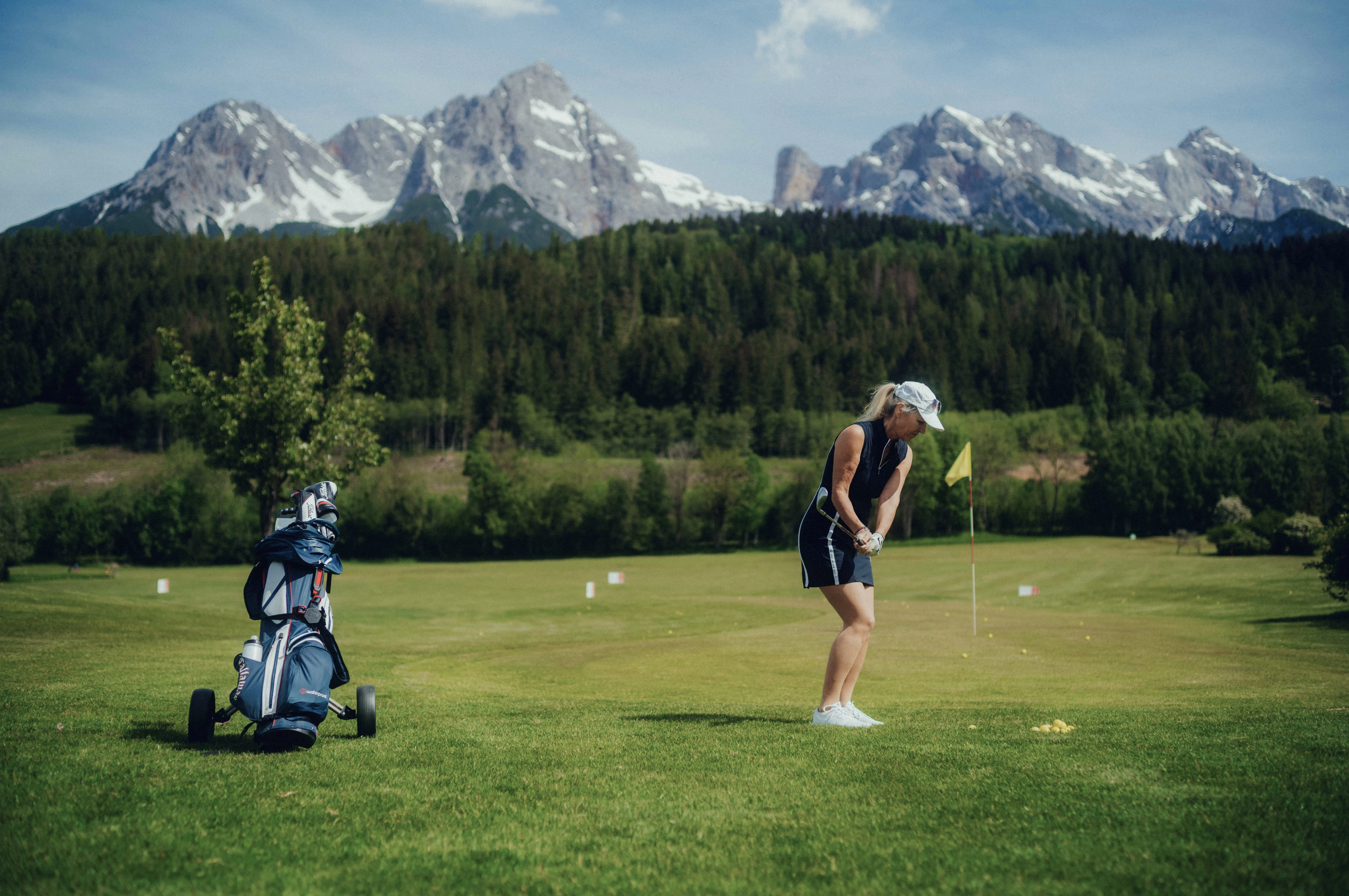 Golfplatz mit golfer, Bergen im Hintergrund und Golftasche.