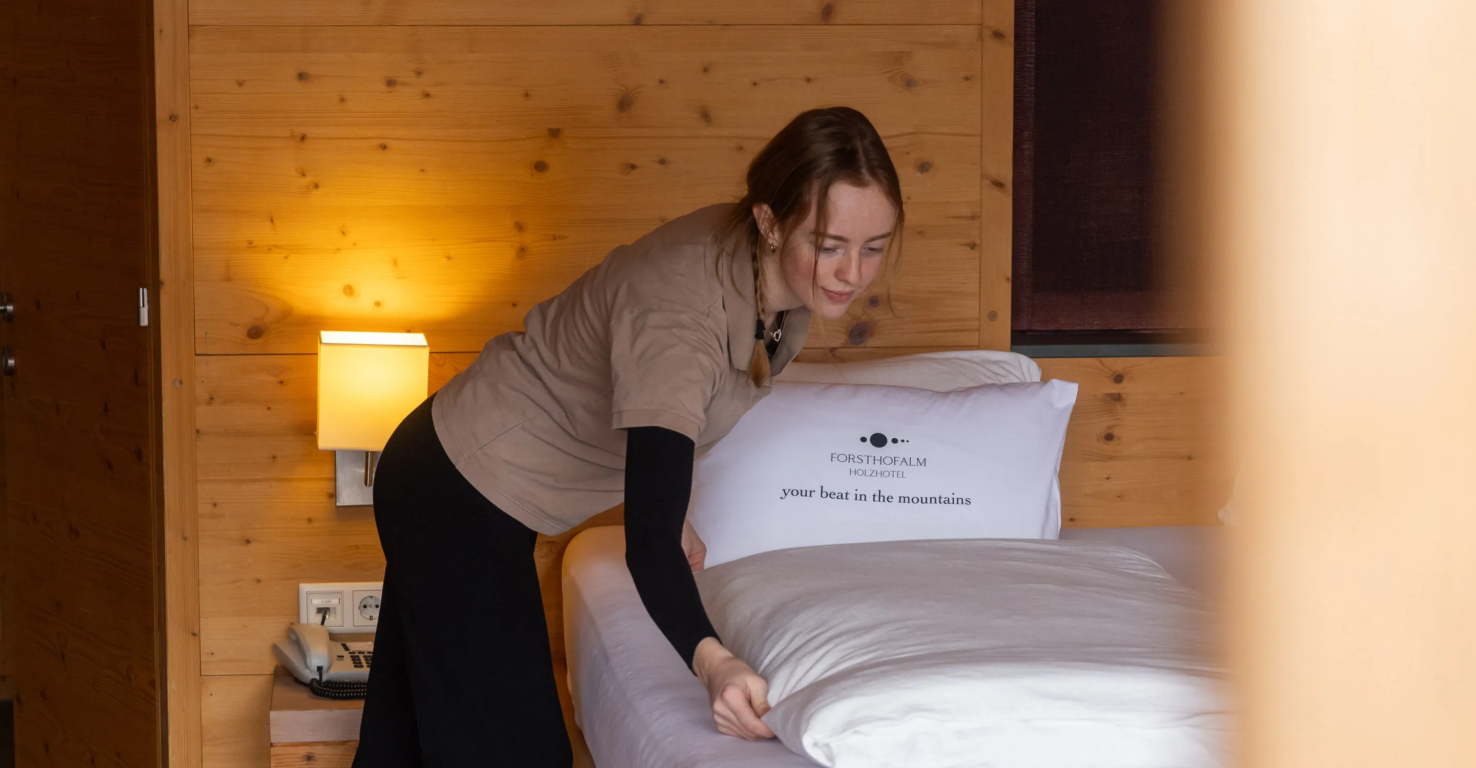 Frau steht neben einem Bett in der Forsthofalm.