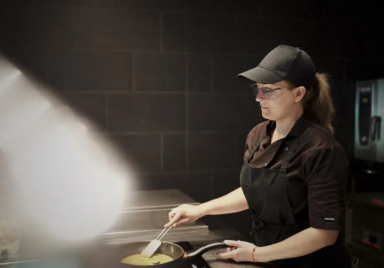 Köchin, die am Herd mit einer Pfanne arbeitet