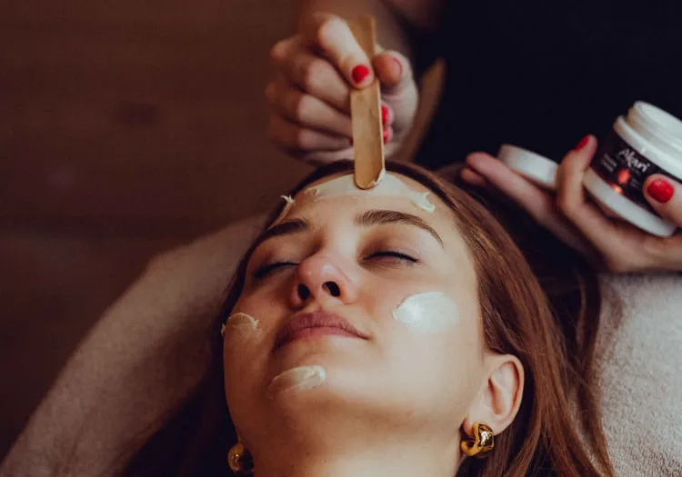 Frau erhält Gesichtsmaske in Spa-Bereich des Holzhotel Forsthofalm