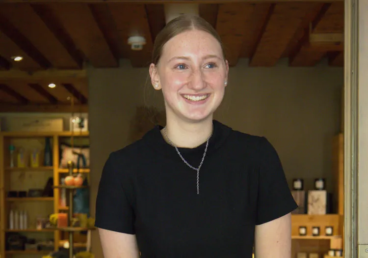 Smiling young woman in a store with wooden ceiling and products displayed