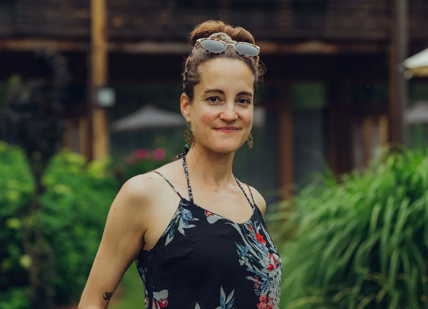 Person in floralen Kleid mit Sonnenbrille, im Freien in einer grünen Umgebung