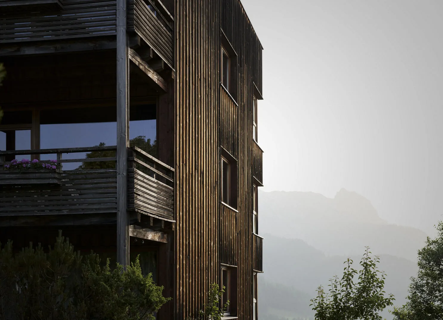 Holzgebäude mit Balkonen vor einer nebligen Bergkulisse