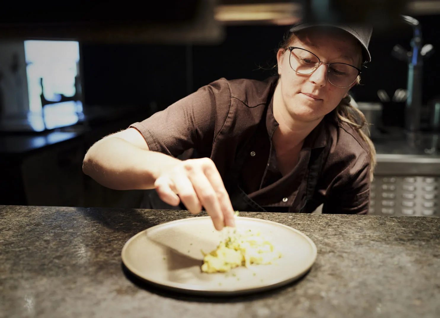 Koch bereitet Essen auf einem Teller in einer Küchenszene zu