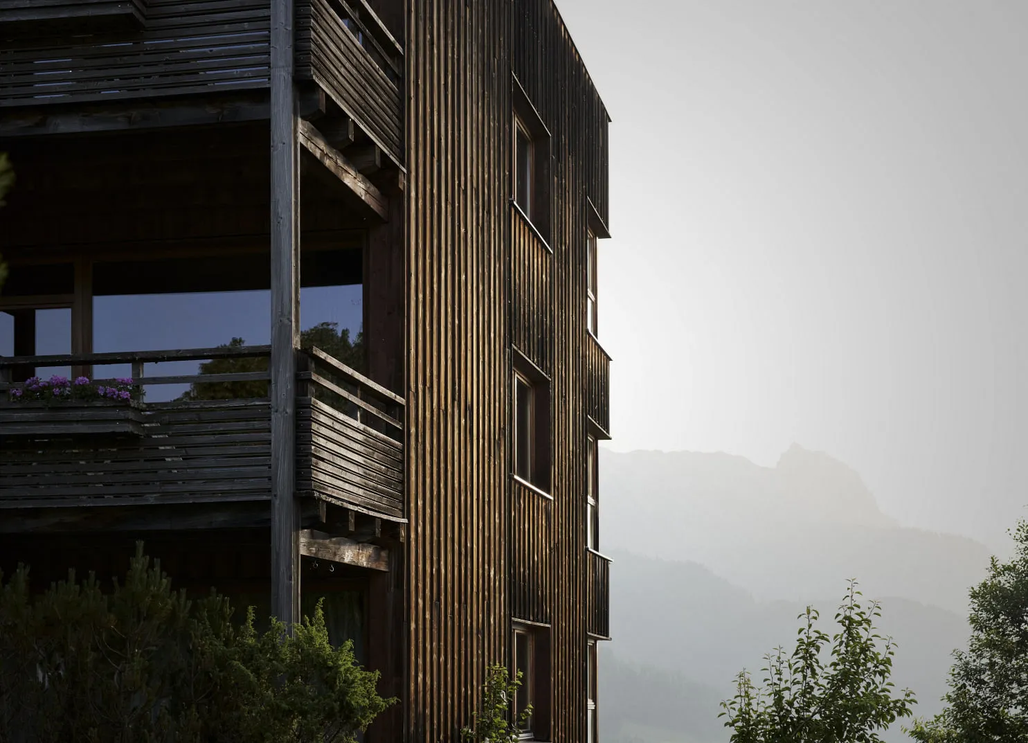 Holzgebäude mit Bergkulisse und Grünpflanzen