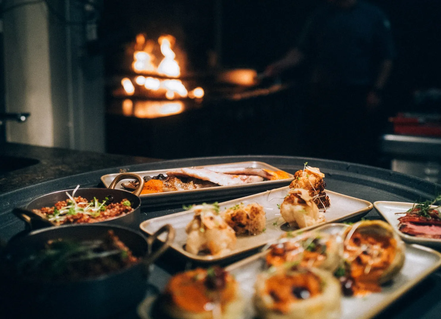 Küchenchef-Gerichte auf Platten, Hintergrund mit Feuerstelle