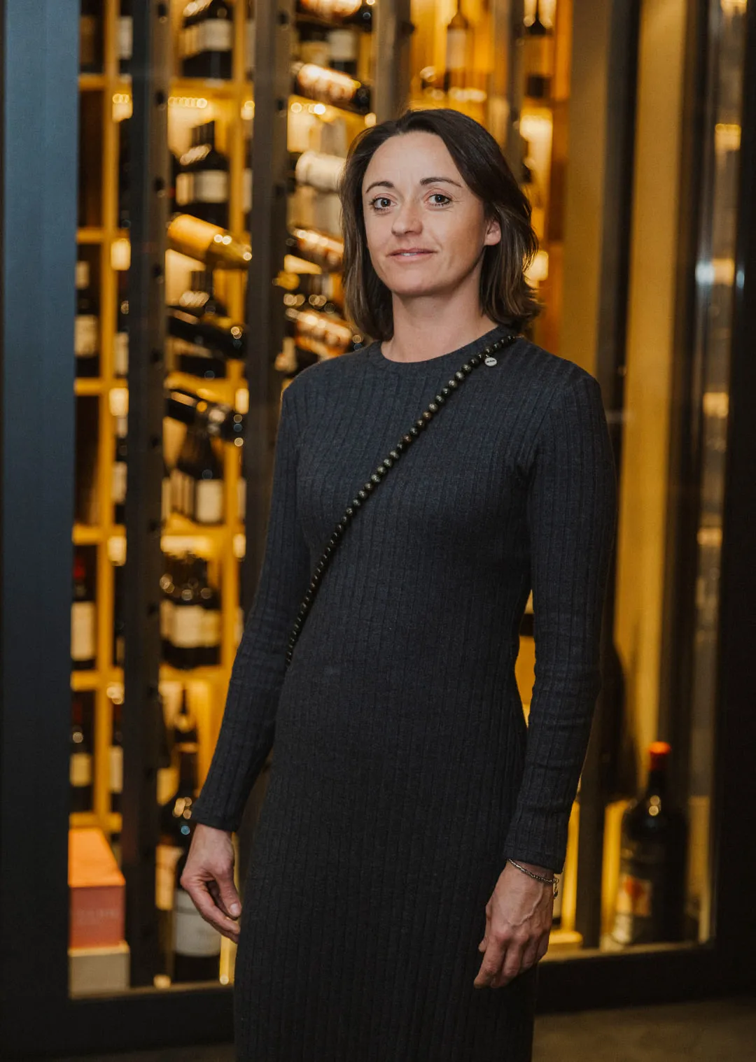 Frau in schwarzem Kleid vor Weinfassregal im Holthotel Forsthofalm