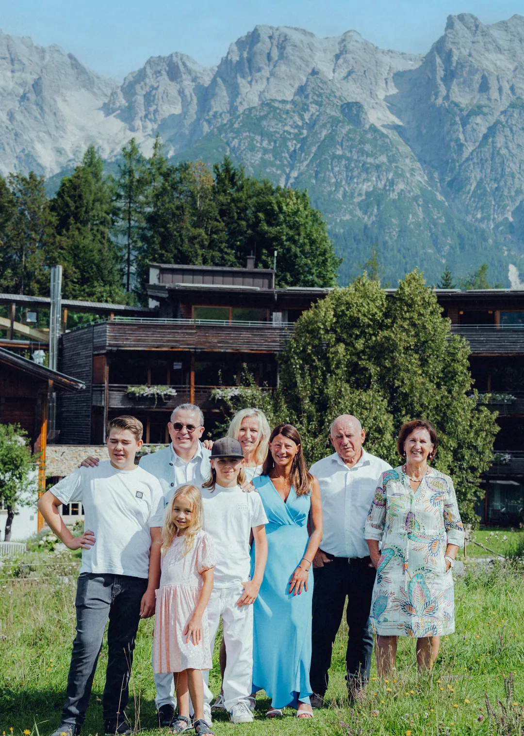 Gruppe von Menschen vor dem Holzhotel Forsthofalm in Leogang, mit Bergen im Hintergrund