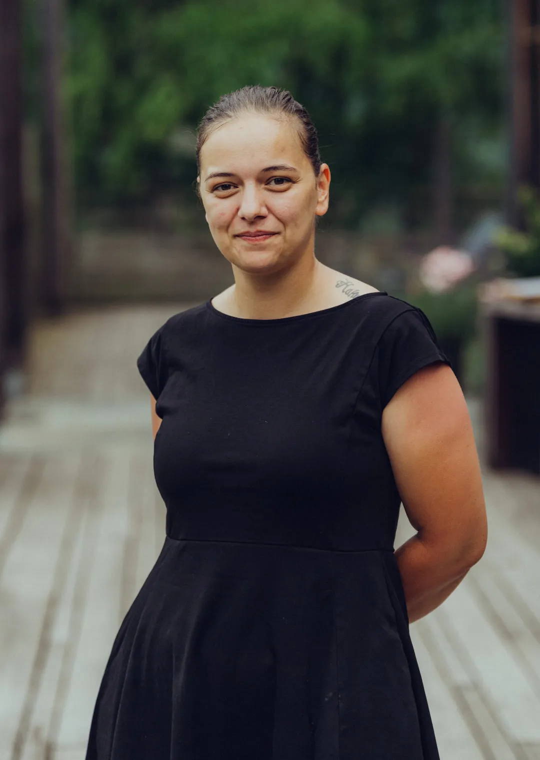 woman in a black dress standing on a wooden deck