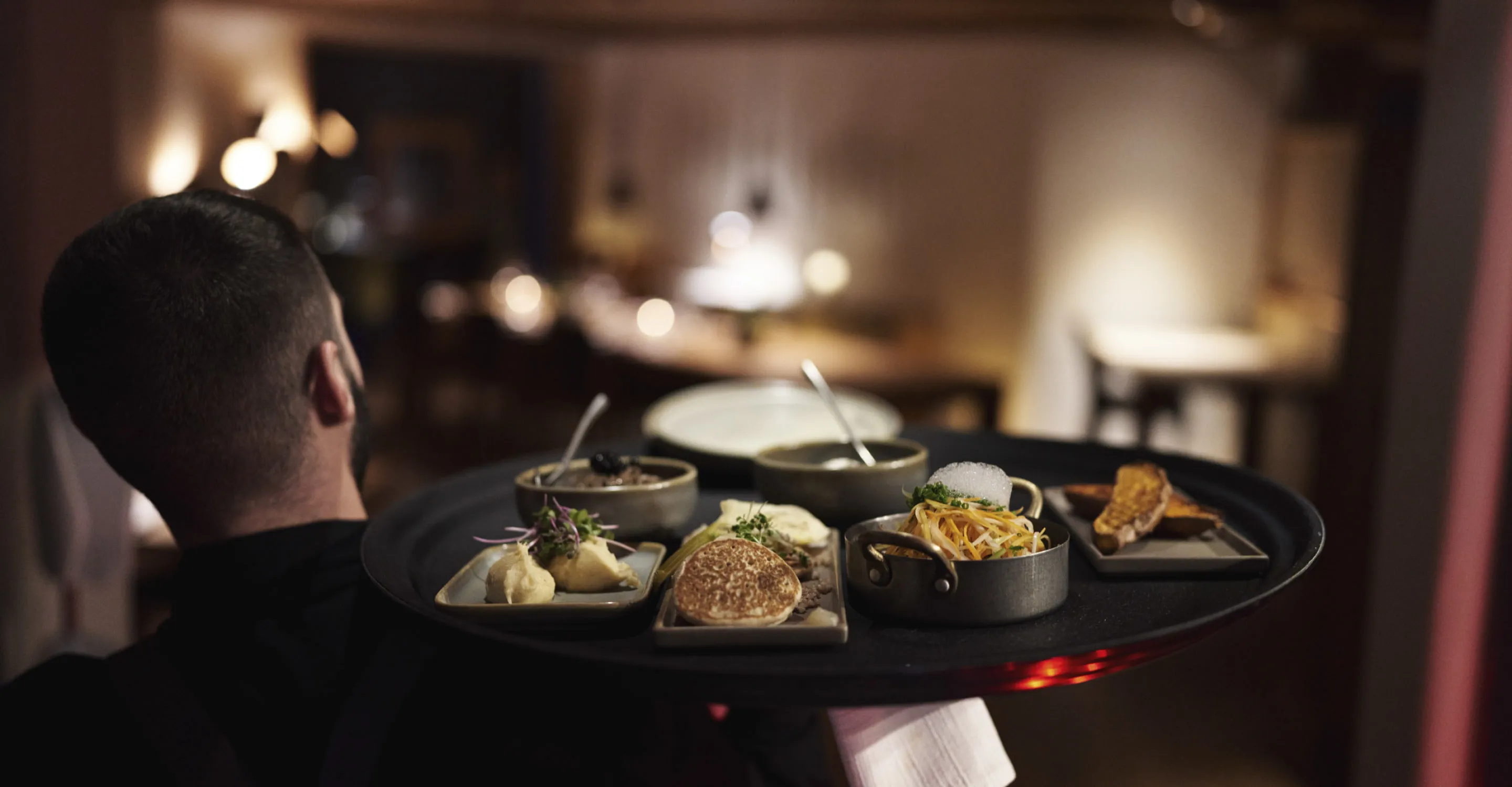 Server presenting dishes at Holzhotel Forsthofalm.
