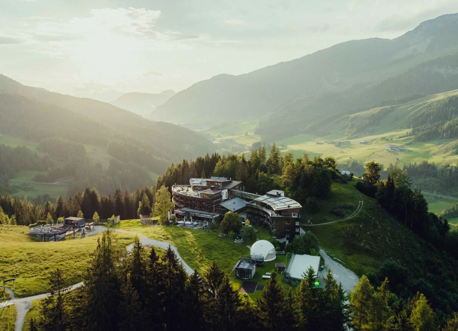 Luftaufnahme eines modernen Gebäudes in einer bergigen Landschaft bei Sonnenuntergang