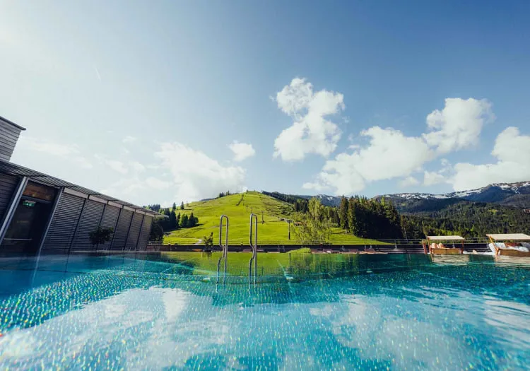 Blick auf einen Pool im Holzhotel Forsth mit grünen Hügeln im Hintergrund