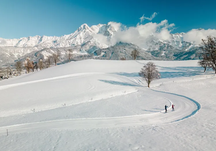 Langlaufen auf einer verschneiten Landschaft mit Bergen im Hintergrund
