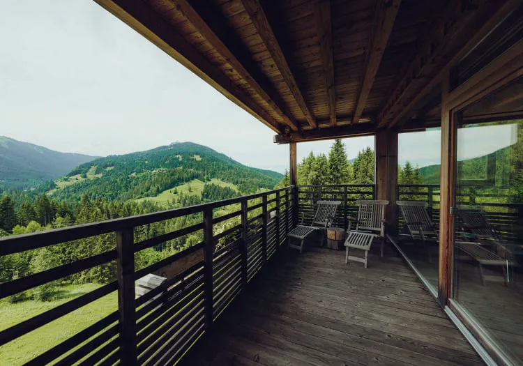 Balkon mit Aussicht auf grüne Hügel und Berge, ruhige Sitzgelegenheiten.