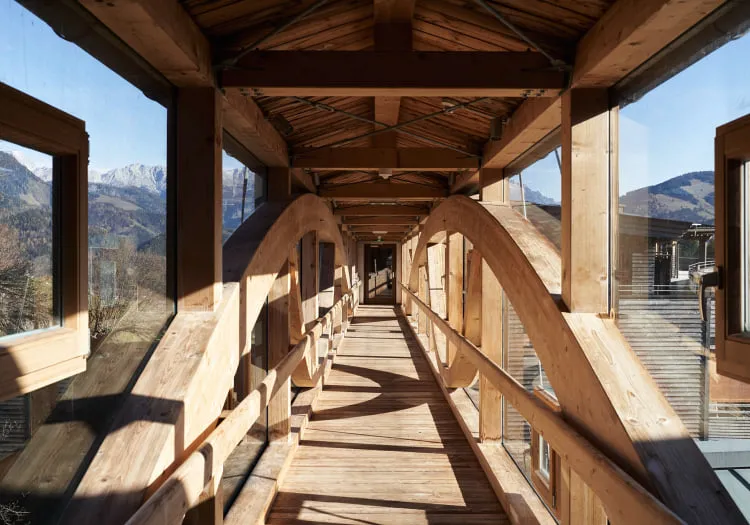Holzgang mit großen Fenstern und Aussicht auf Berge