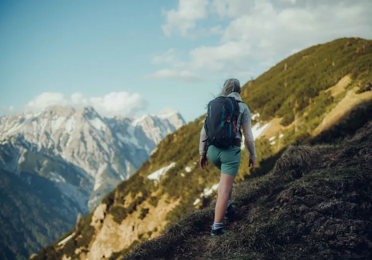 Wanderer auf einem Bergweg mit Blick auf die Alpen