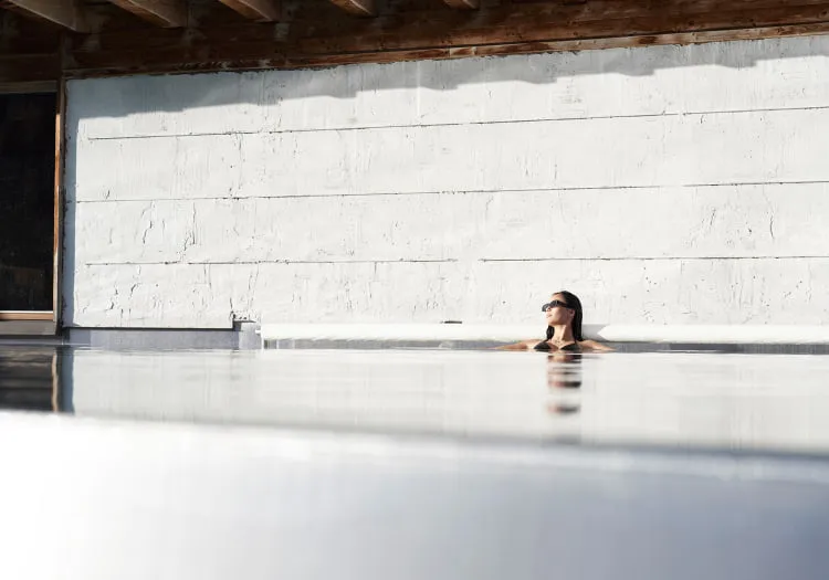 Person entspannt in einem Pool neben einer weißen Wand