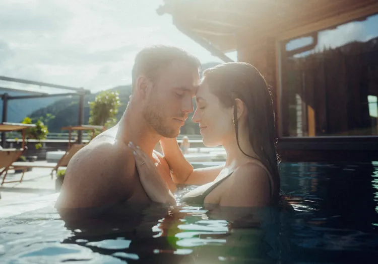 Paar im Wasser des Holzhotel Forsthofalm in Leogang