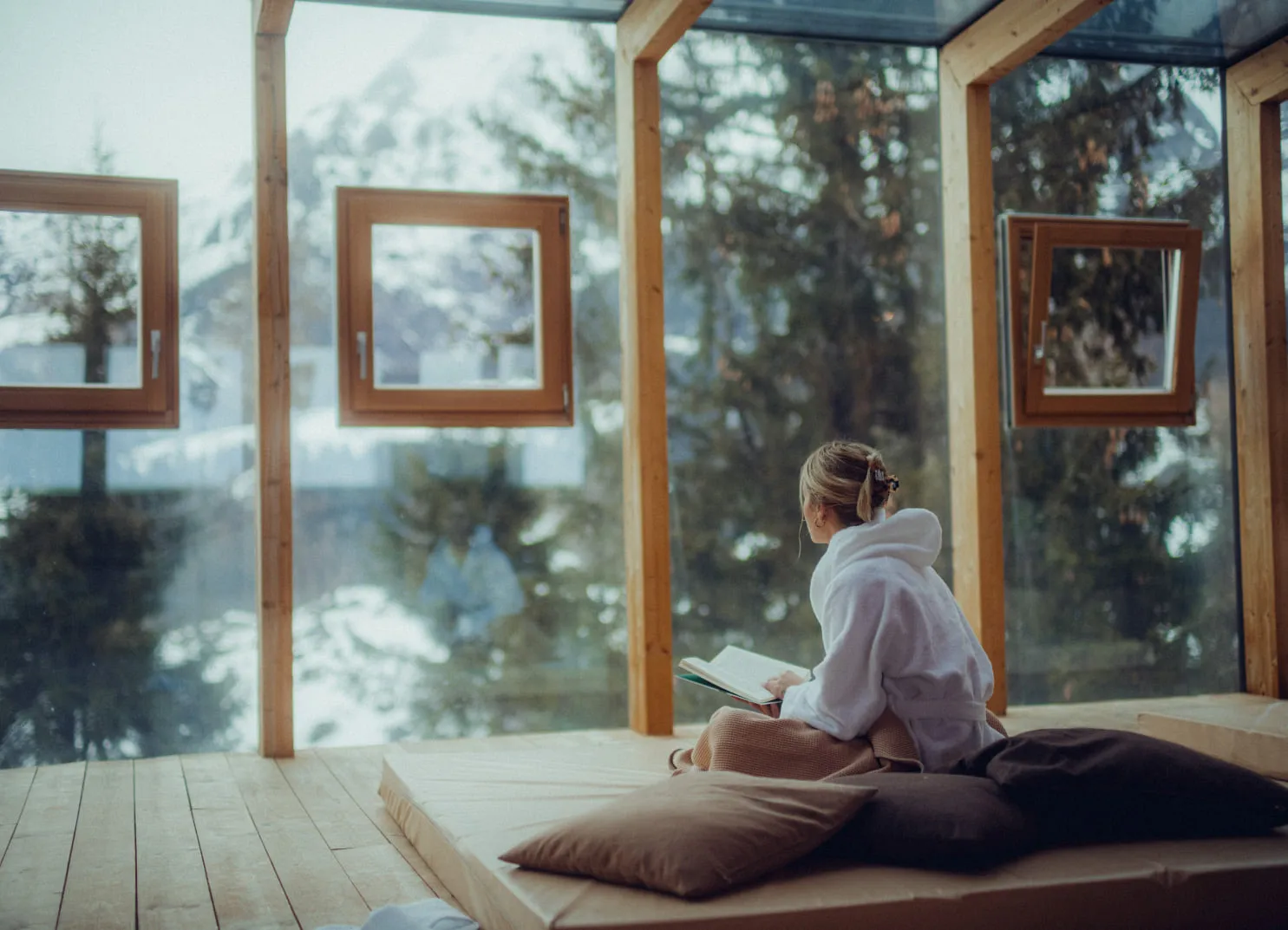 Kind in einem Holzhotel mit Ausblick auf die Berge und Fensterrahmen.