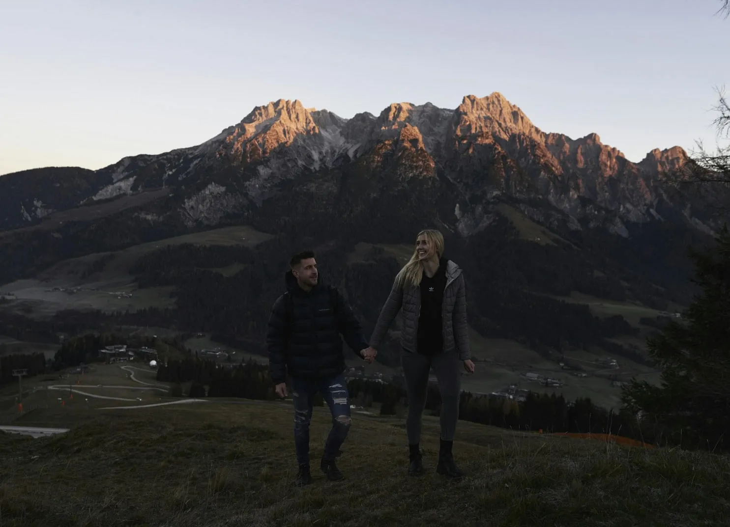 Couple holding hands in front of mountains at sunset