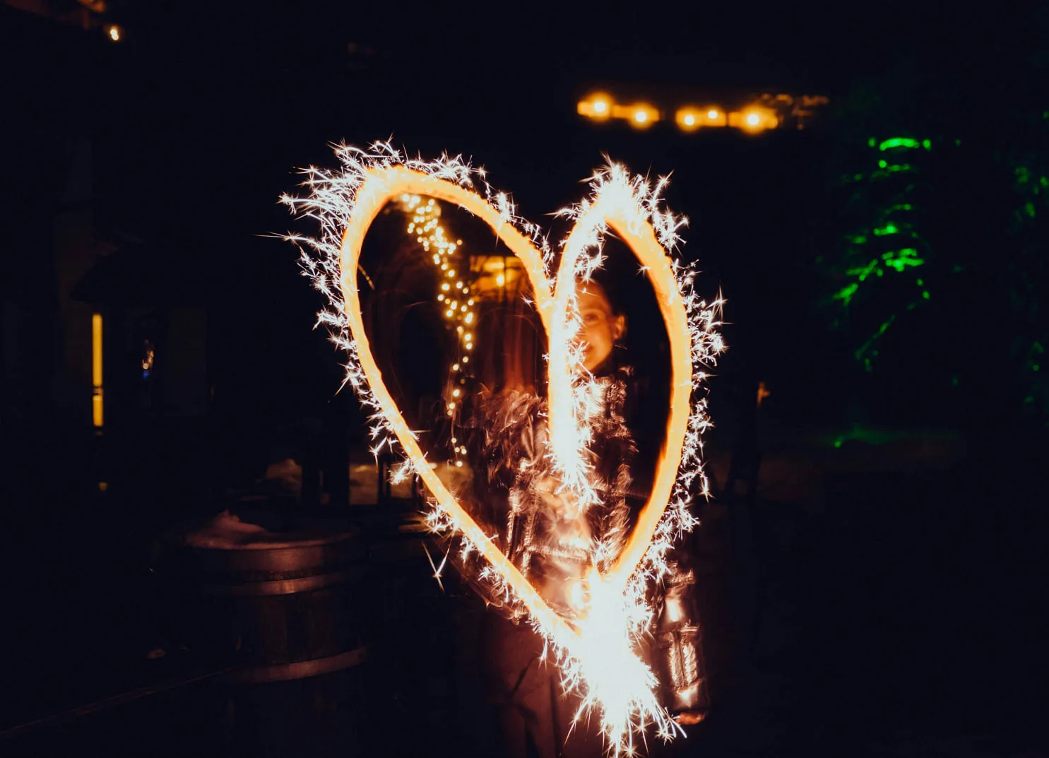 A person draws a heart with a sparkler at night.