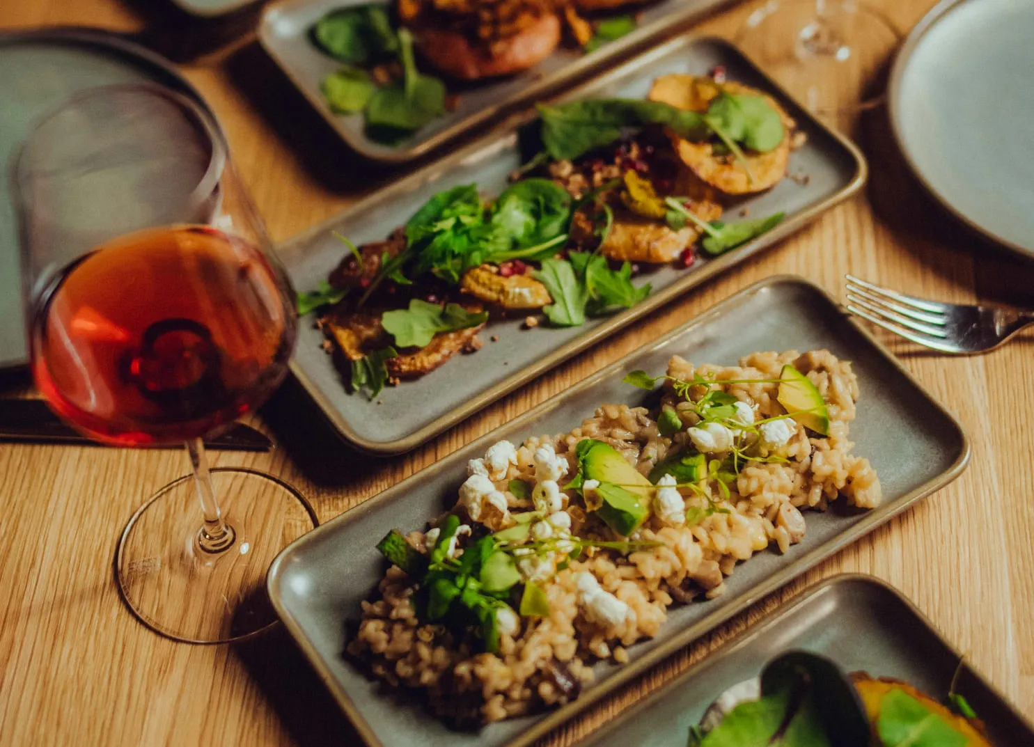 Plates of risotto and salad with a glass of red wine on a wooden table