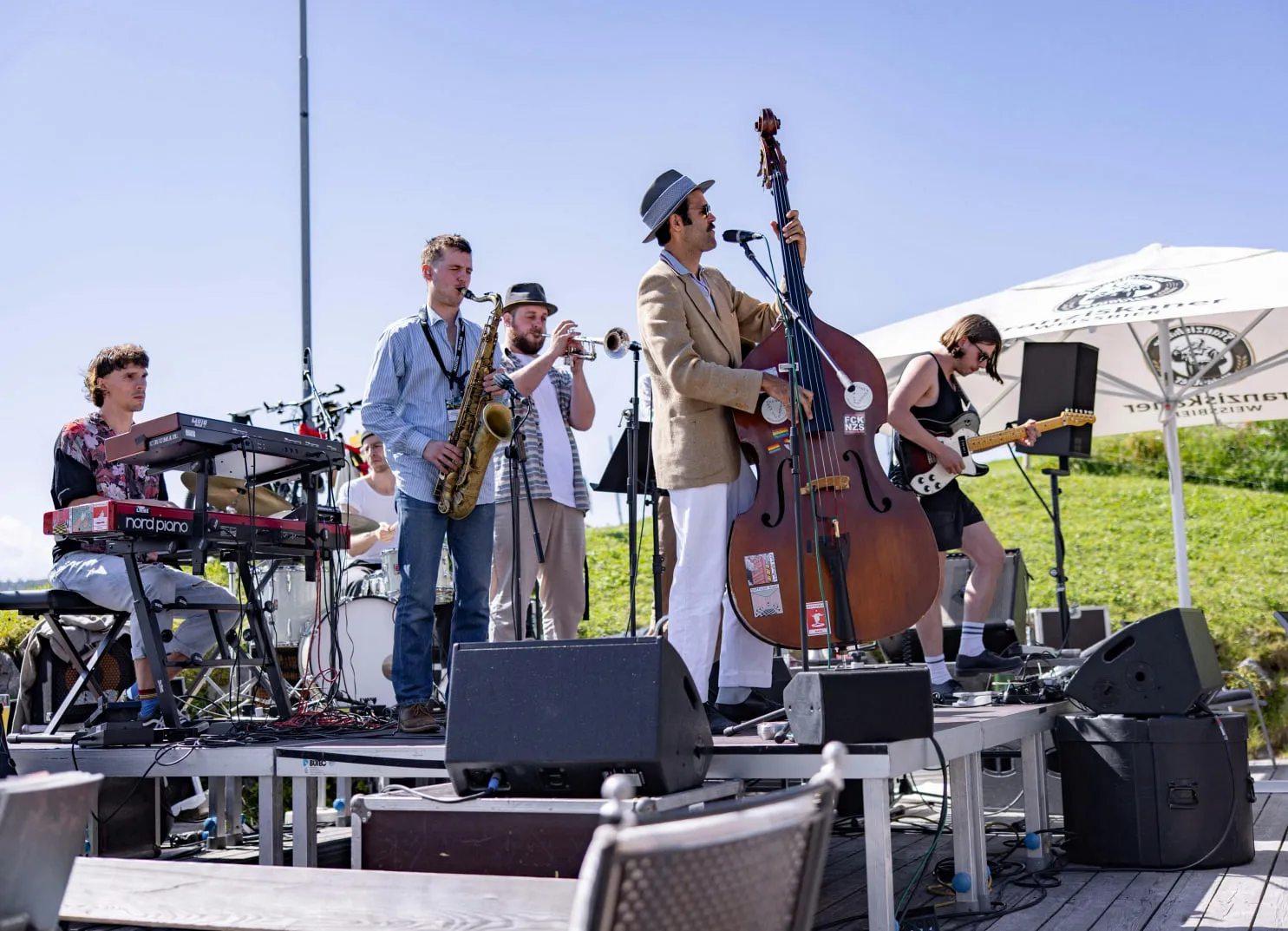 Eine Band spielt live im Freien, Sänger mit Kontrabass, Musiker am Keyboard, Saxophon und Schlagzeug.