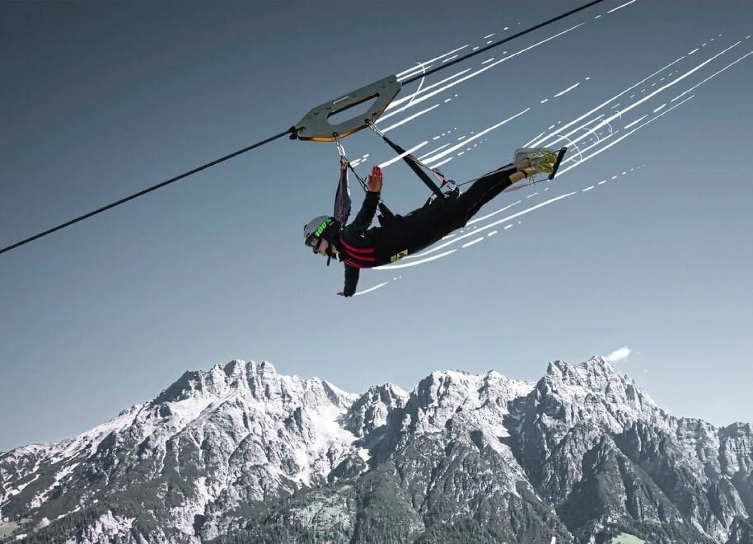 Person gliding on a zipline over snow-covered mountains