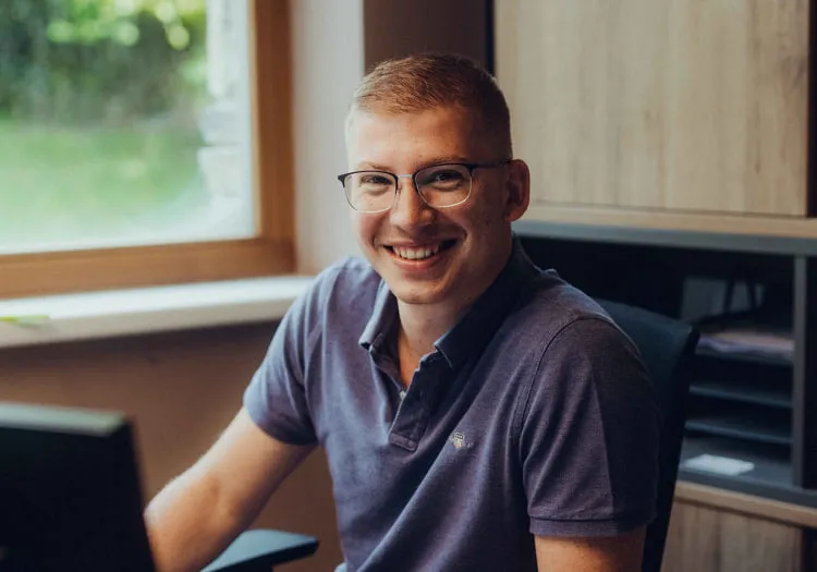 Smiling person at a desk in Holzhotel Forsth