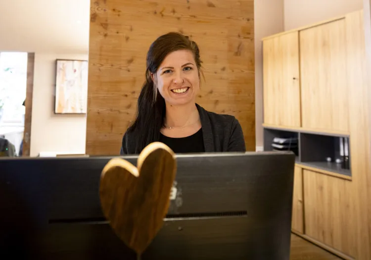 Smiling woman at reception desk with wooden details in background