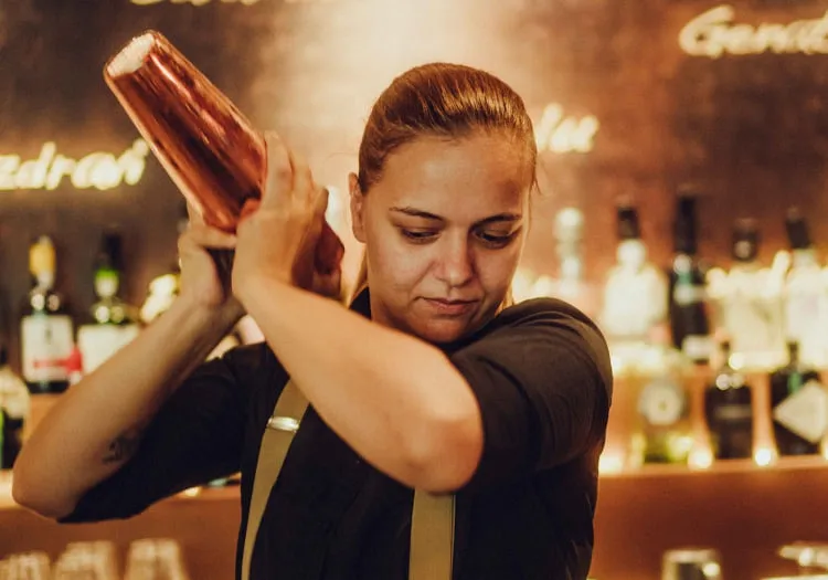 Woman mixing cocktails behind a bar at Holzhotel Forsth