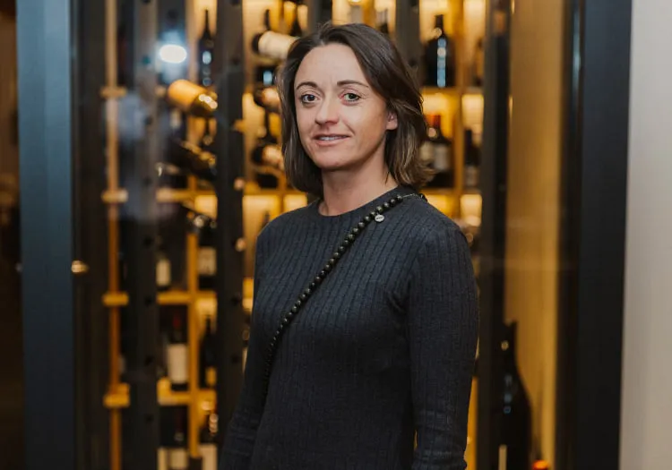 Person in front of a wine cellar with bottles