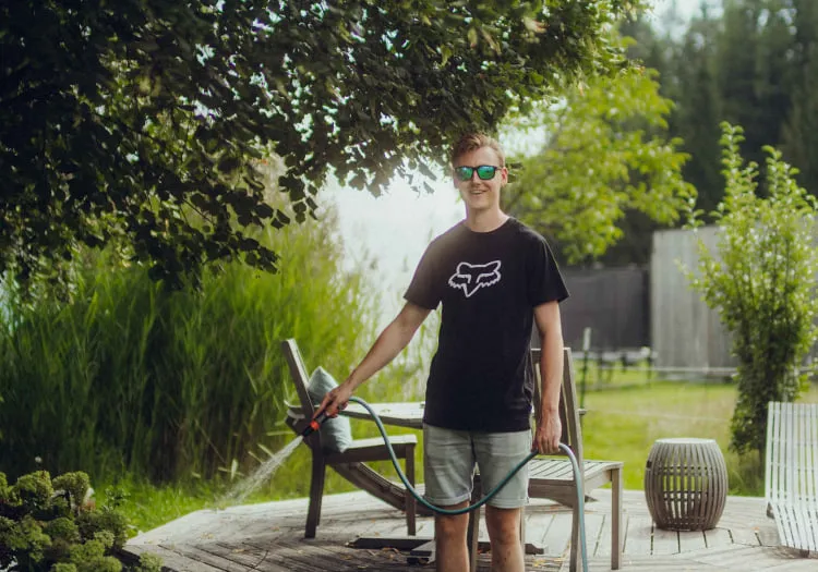 Young man watering plants in the garden of Holzhotel Forsth.