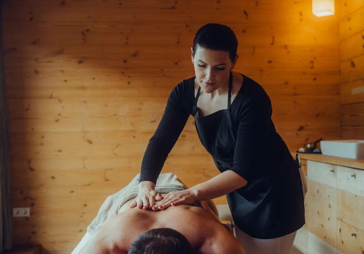 Woman giving a massage in a wooden hotel room