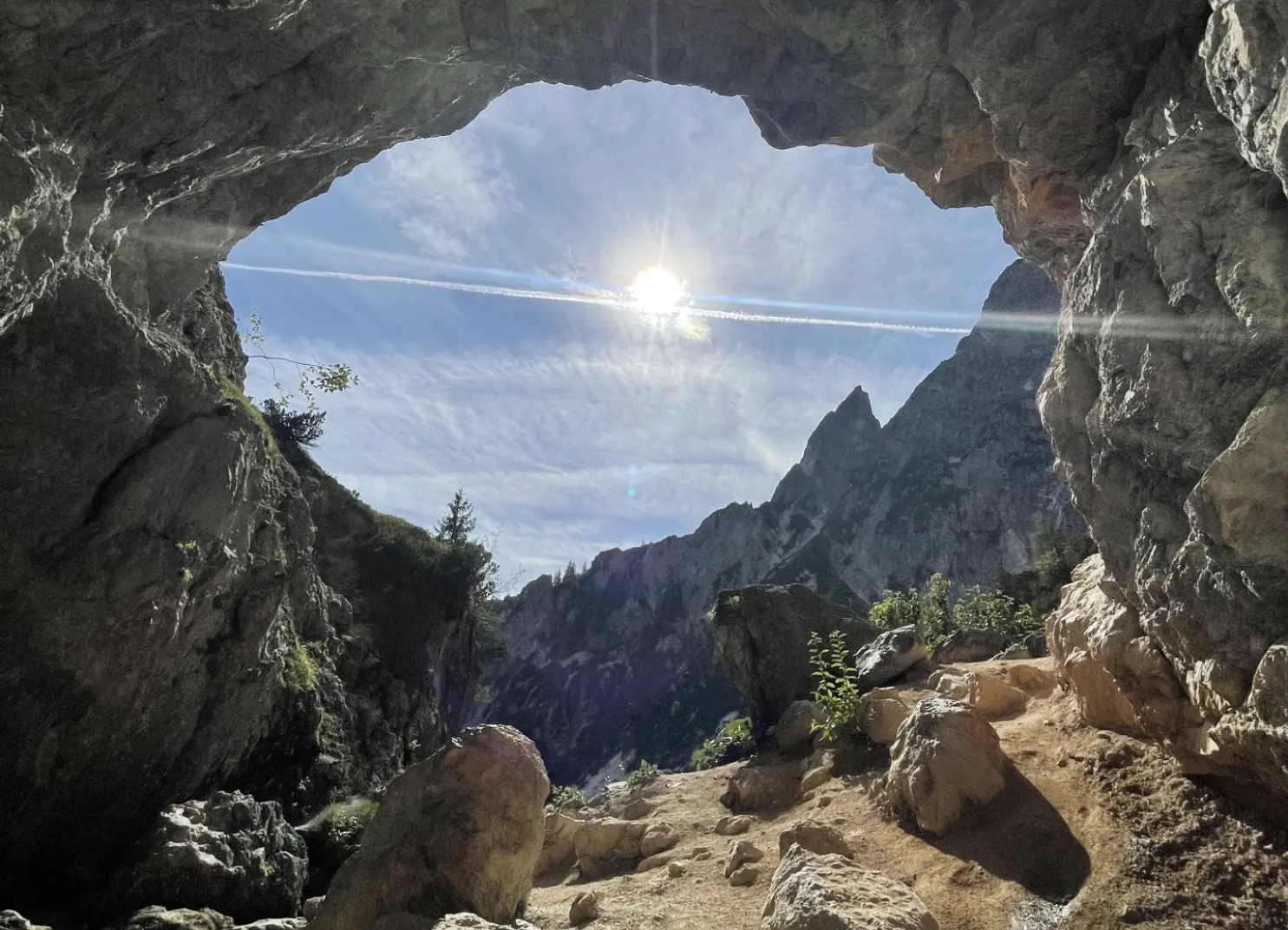 Blick aus einer Höhle auf Berge und Himmel