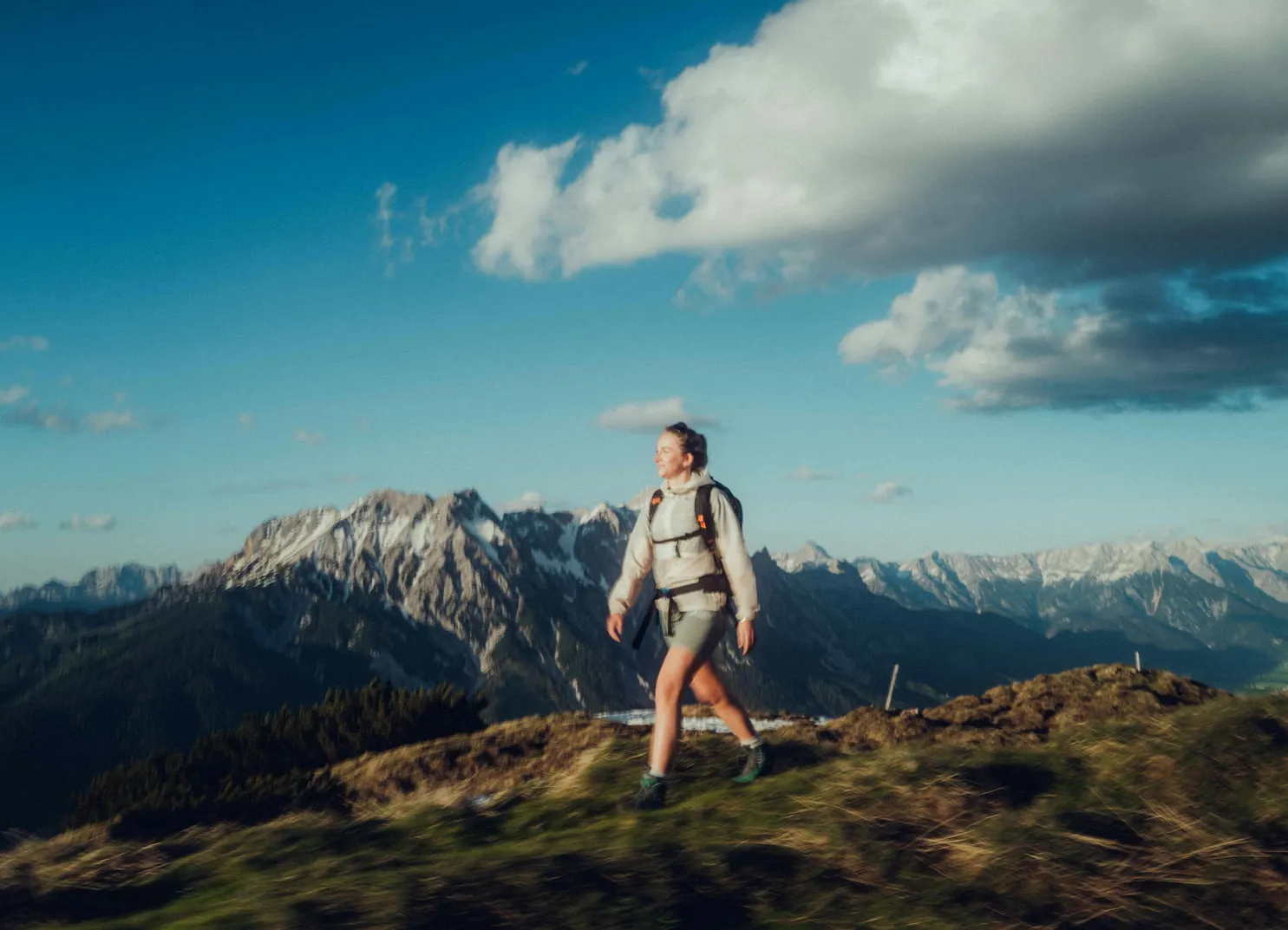 Frau wandert in den Bergen unter blauem Himmel