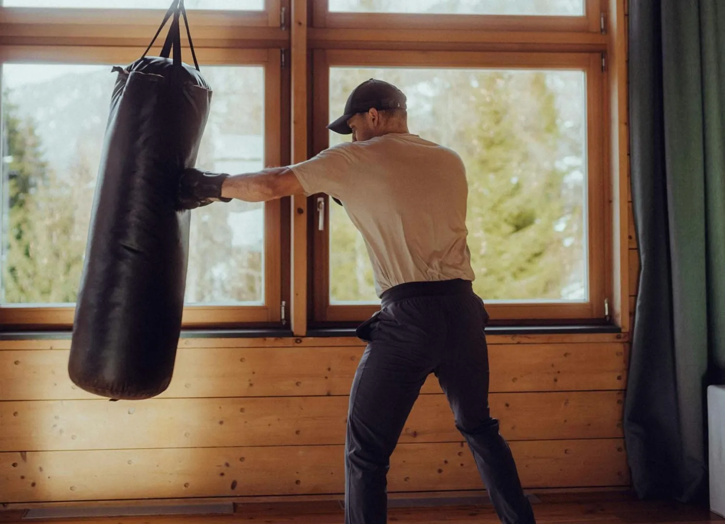 Person trainiert mit einem Boxsack in einem Raum mit großen Fenstern