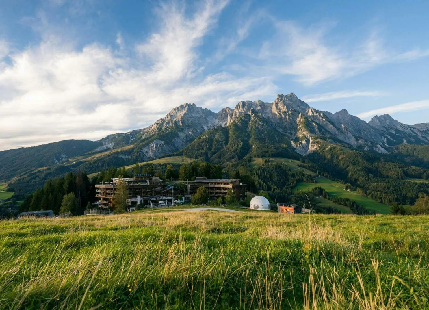 Blick auf die Berge mit einer Unterkunft im Vordergrund und grünem Gelände