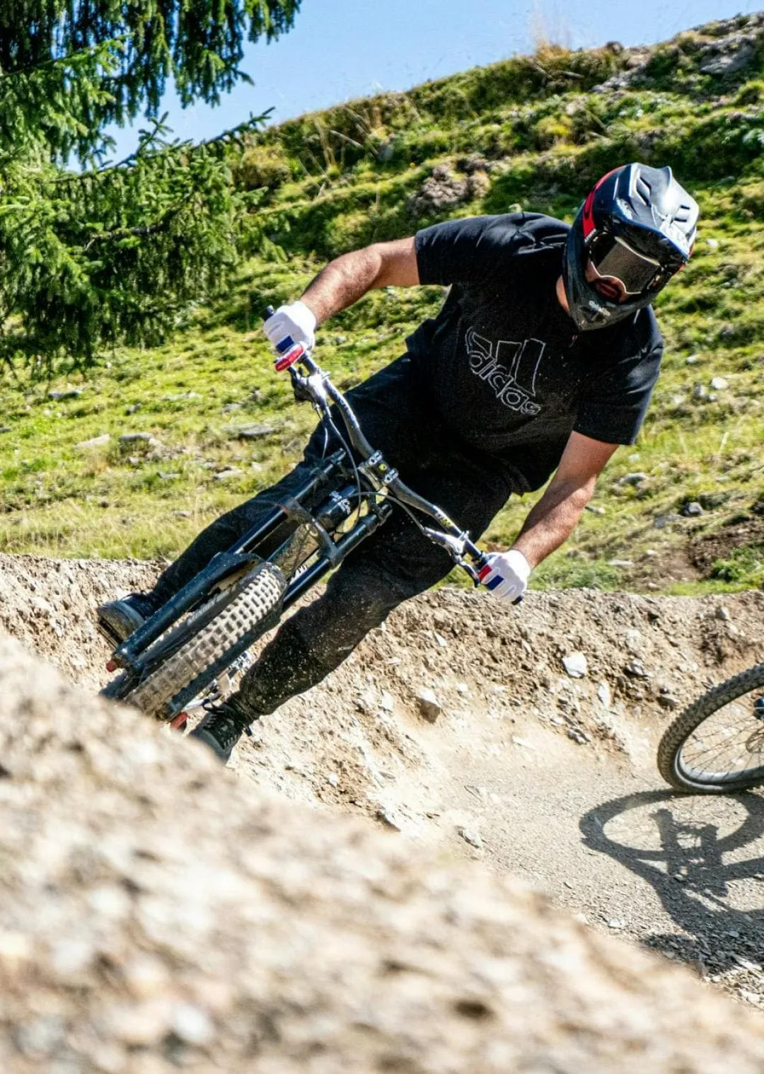 Mountainbiker auf einem Dirttrack mit Bäumen im Hintergrund