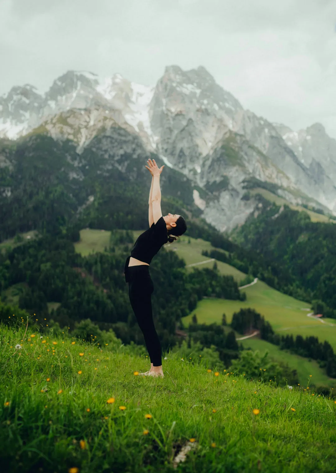 Person stretching with arms raised in a mountain landscape