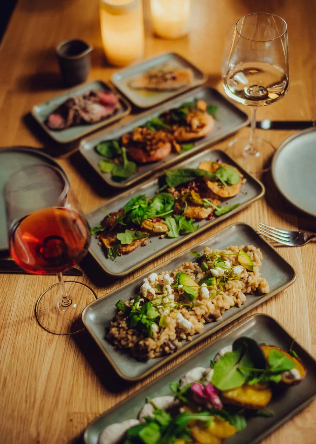 various gourmet dishes on wooden table with drinks and candles