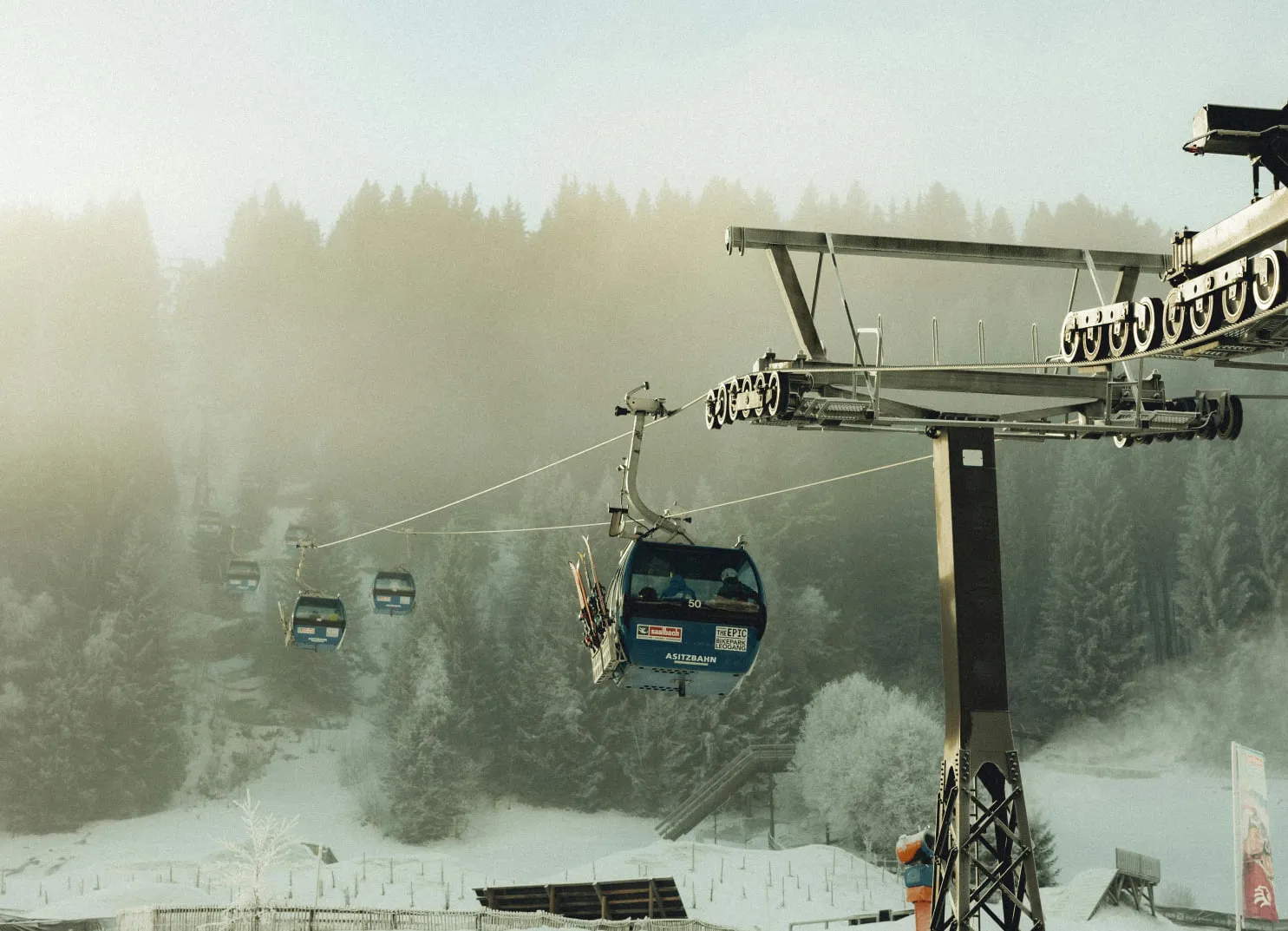 Seilbahn mit blauen Gondeln zwischen verschneiten Bäumen