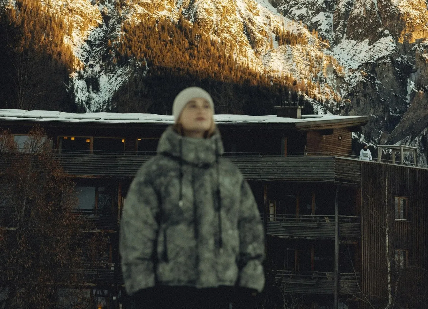 Person in winterlicher Kleidung vor alpiner Landschaft.