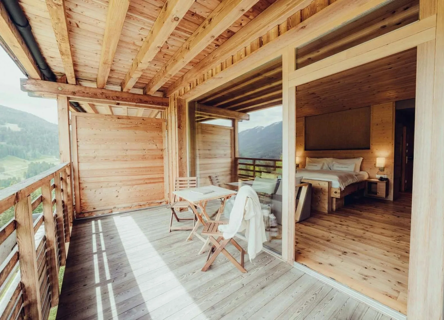 Wooden balcony with table and chairs, overlooking a scenic view